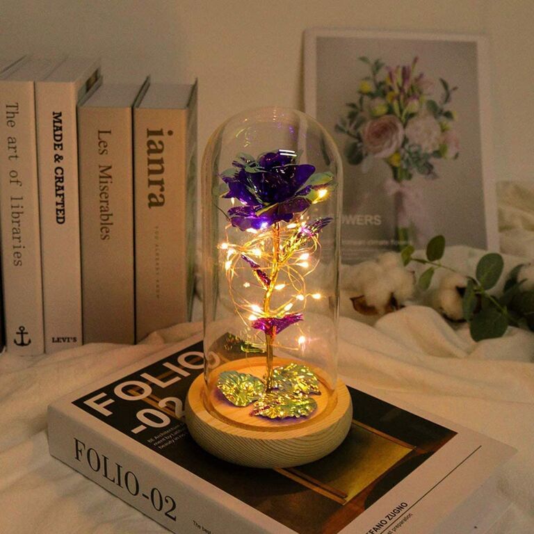 A purple and gold rose surrounded by fairy lights in a glass dome from Etsy