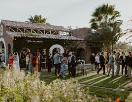 outdoor wedding cocktail hour with guests on lawn in front of stone building