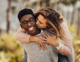 how to talk about marriage young couple with man giving piggy back ride to girlfriend kissing him on the cheek