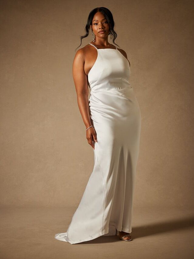 Model wears a sleeveless white wedding dress. 