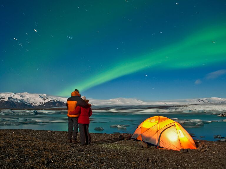 couple hugs as they watch the northern lights dazzle across iceland