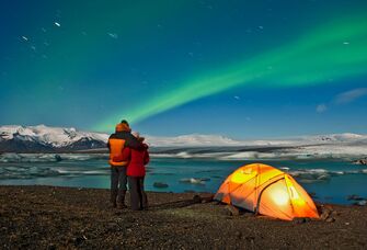 couple hugs as they watch the northern lights dazzle across iceland