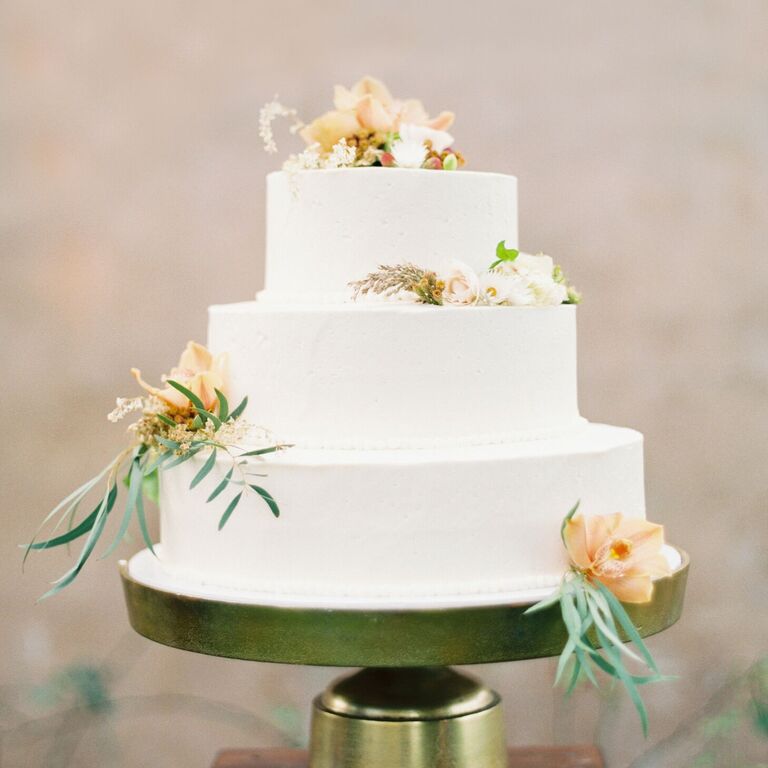 Minimal white three-tier wedding cake on gold cake stand