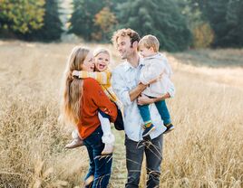 Couple in field holding two small children