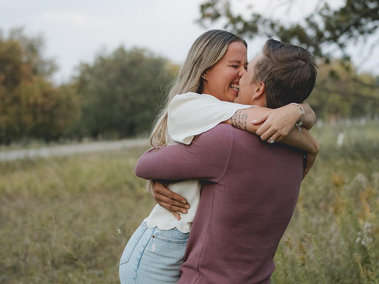 Couple hugging and kissing for a romantic picture in a field