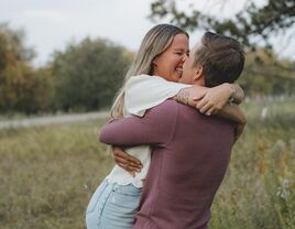 Couple hugging and kissing for a romantic picture in a field